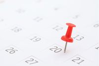 Imagem de um calendário com um alfinete vermelho marcando o dia 20. Os números dos dias estão em cinza sobre um fundo branco. A imagem transmite a ideia de data importante ou evento marcado