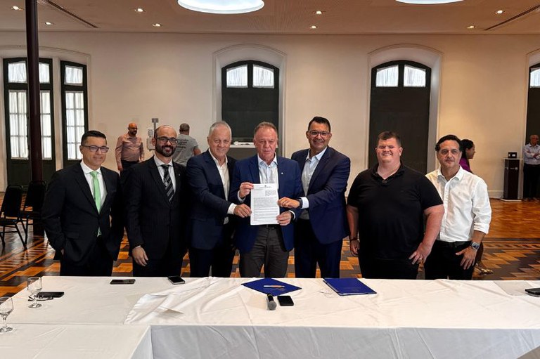 foto mostra autoridades em pé lado a lado segurando um papel