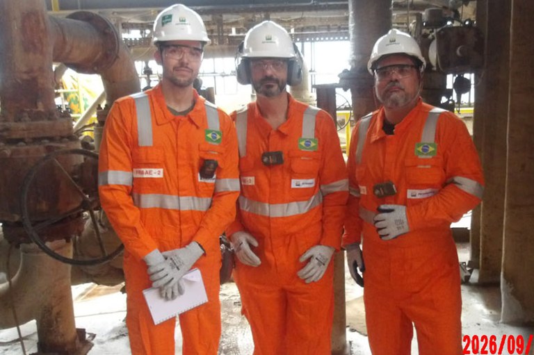 Foto mostra integrantes que fizeram as vistorias em plataformas marítimas de petróleo. Estão com roupas típicas de petroleiros, de cor laranja.