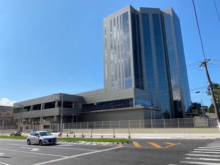 Foto de um prédio alto, espelhado, com uma dia de céu azul