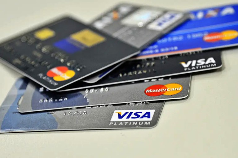 Foto mostra vários cartões de crédito em cima de uma mesa