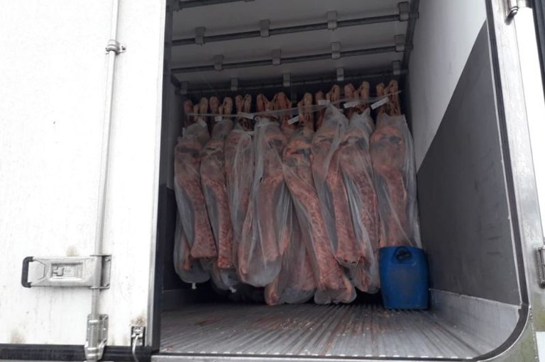 Foto mostra um caminhão frigorífico com as portas abertas mostrando carnes penduradas