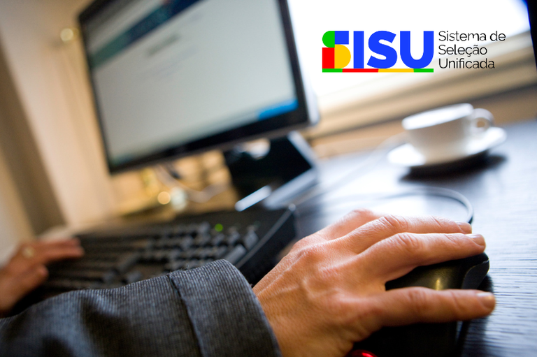 A câmera foca em uma mão mexendo no mouse, de alguém que está mexendo no computador. No centro da imagem há a logo do SISU - Sistema de Seleção Unificada.