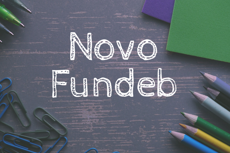 A imagem apresenta a frase "Novo Fundeb" centralizada em uma fonte branca que simula o traçado de giz ou caneta. O fundo possui uma textura cinza escura que remete a uma lousa ou mesa de madeira desgastada, sendo emoldurado por diversos materiais escolares nas bordas, como lápis de cor, clipes, canetas e papéis coloridos. O conjunto visual utiliza essa estética lúdica para contextualizar o tema da educação de forma direta e amigável.