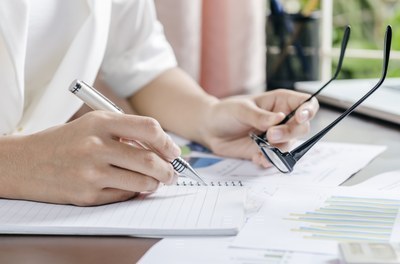 Pessoa escrevendo em um livro com uma caneta