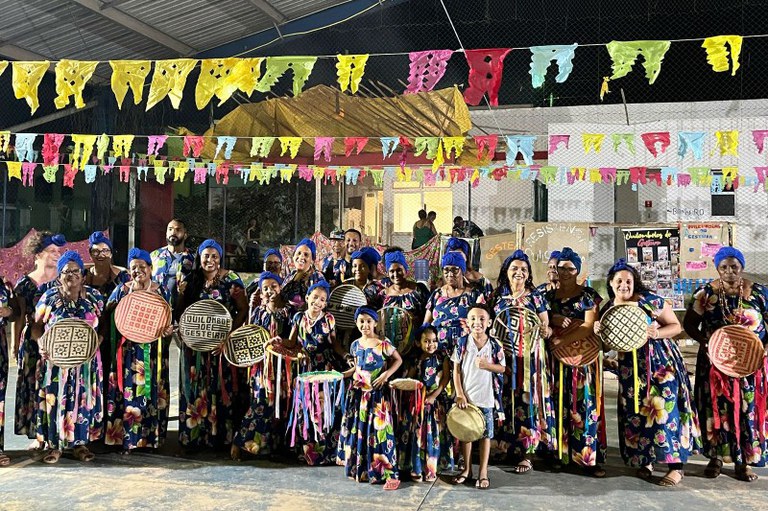 Foto mostra a comunidade Gesteira com roupas típicas e segurando artesanato
