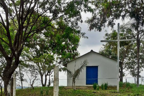 Foto mostra uma igrejinha com paredes brancas e uma porta azul