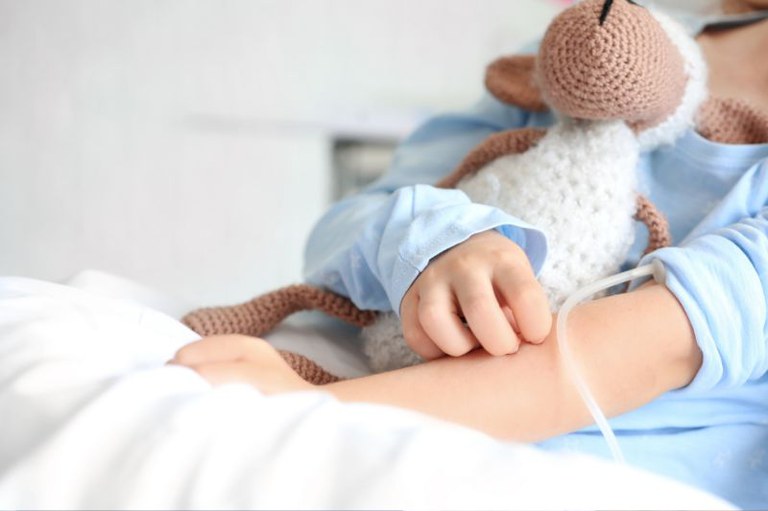 foto em detalhe mostra uma criança no hospital segurando um bichinho de pelúcia