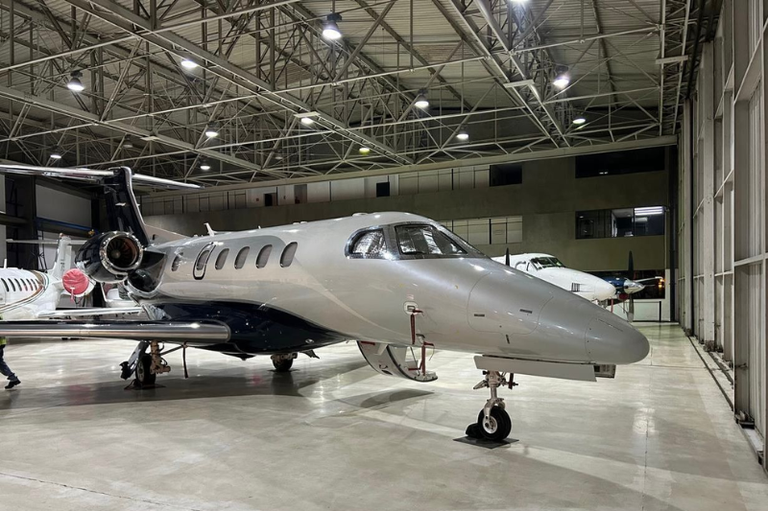 Foto mostra uma jato executivo dentro de um hangar.