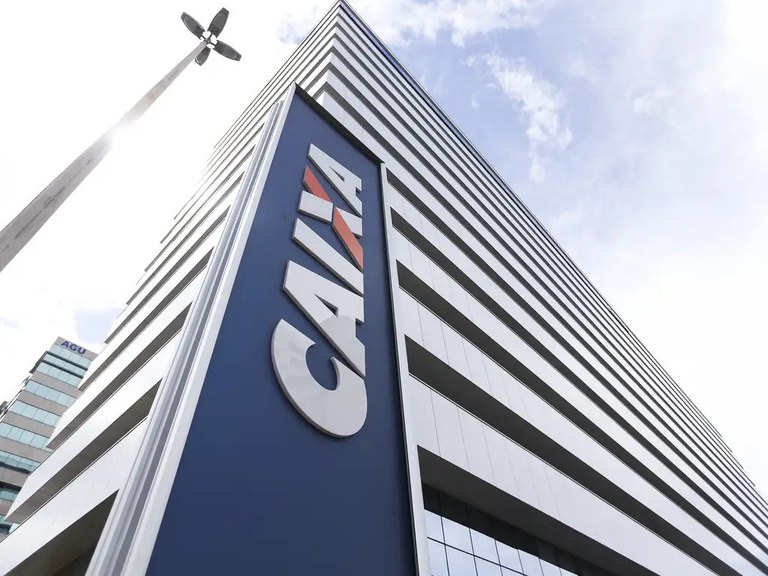 Fotografia mostra a fachada de uma agência da Caixa Econômica Federal, com a logomarca do banco em destaque.