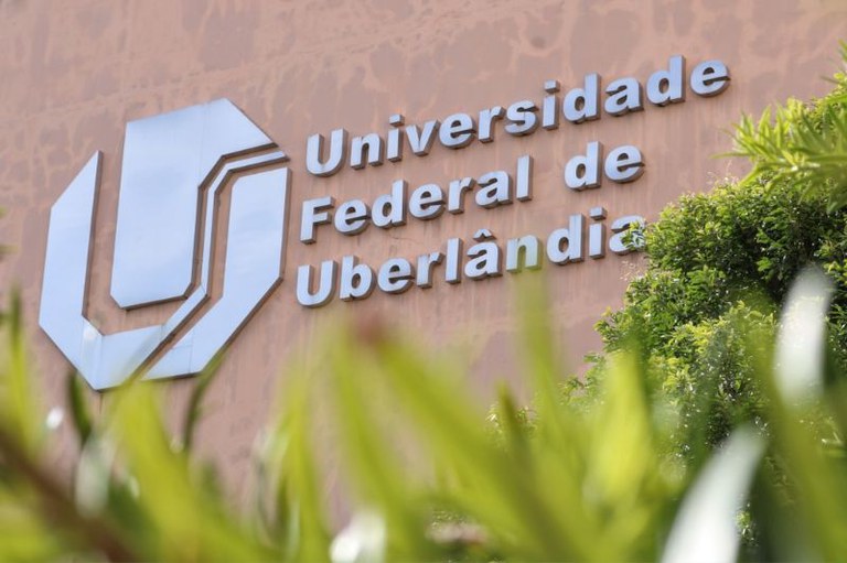 Foto em detalhe mostra fachada da universidade federal de uberlândia com vegetação na frente