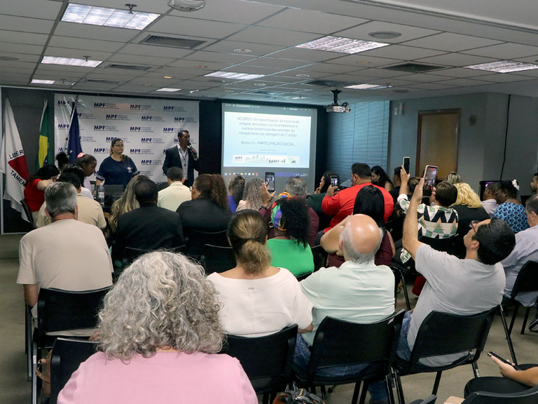 A fotografia mostra um momento do encontro e revela o auditório cheio com o membro do MPF na frente falando para as pessoas.