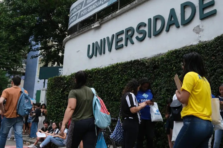 Foto mostra jovens em frente a uma Universidade