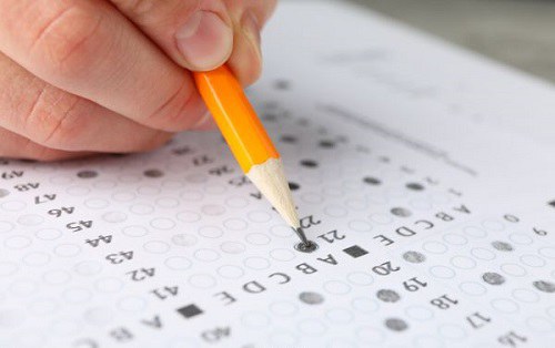Imagem de uma mão assinalando questões de um gabarito.