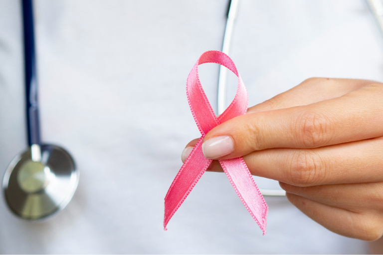 Foto mostra uma pessoa segurando um laço rosa, símbolo do combate ao câncer de mama