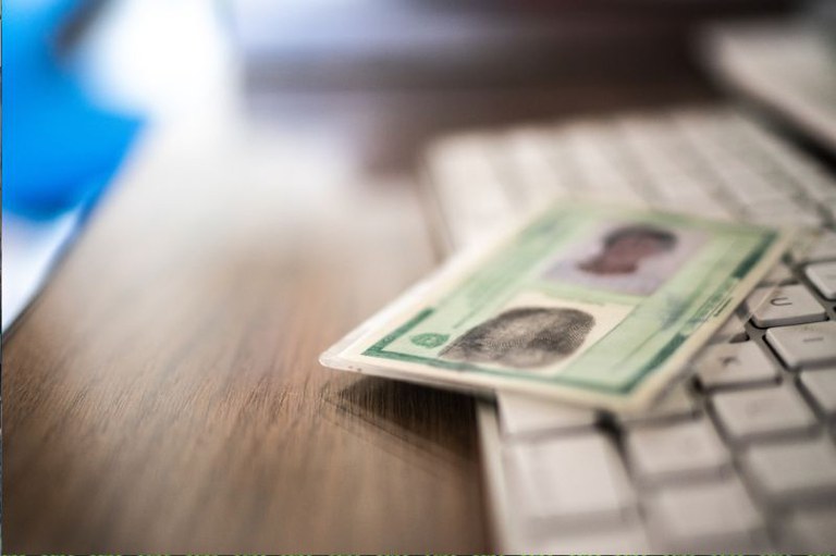 Foto ilustrativa de uma identidade desfocada em cima do teclado de um computador