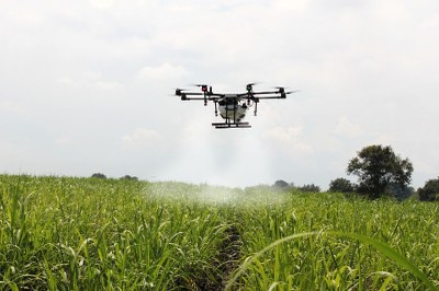 Foto mostra um drone pulverizando uma plantação com agrotóxicos