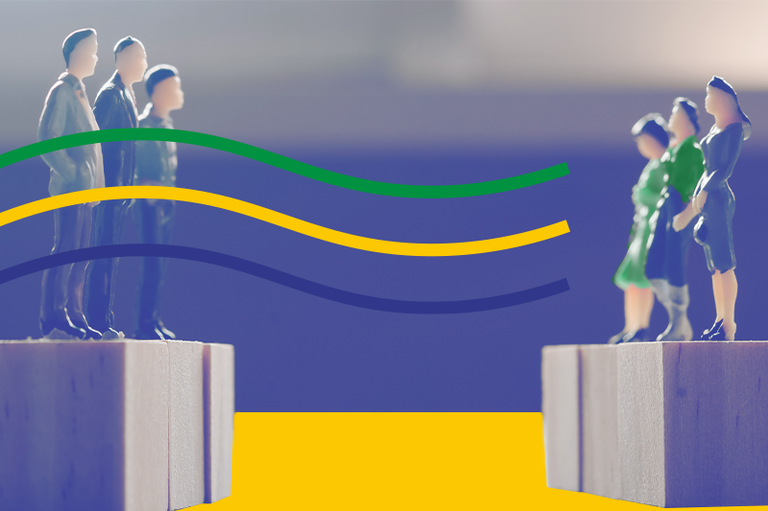 Uma fotografia conceitual mostra miniaturas de pessoas separadas por um abismo sobre bases de madeira. No lado esquerdo, estão três homens de terno cinza; no direito, três mulheres, vestidas de verde e azul. Entre os grupos, uma ponte simbólica é formada por três linhas coloridas (verde, amarela e azul), que saem da altura dos homens em direção às mulheres, destacando a conexão sobre o fundo desfocado com uma faixa amarela na base.
