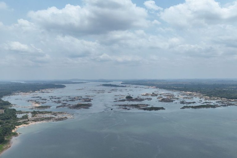 Vista aérea de rio muito largo, repleto de rochas e pequenas ilhas, com florestas densas em ambas as margens sob um céu nublado. É a área do Pedral do Lourenção, no Rio Tocantins, no Pará.