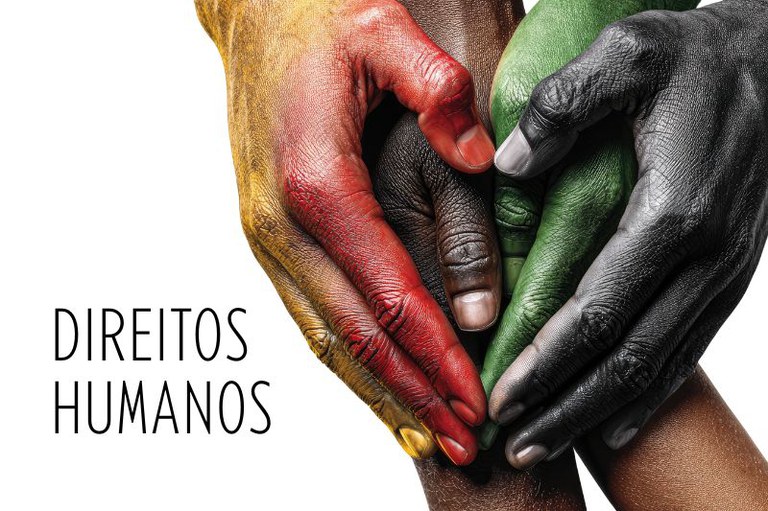 Foto em fundo branco de várias mãos pintadas de cores diferentes unidas, formando o desenho de um coração. No canto inferior esquerdo está o texto Direitos humanos.