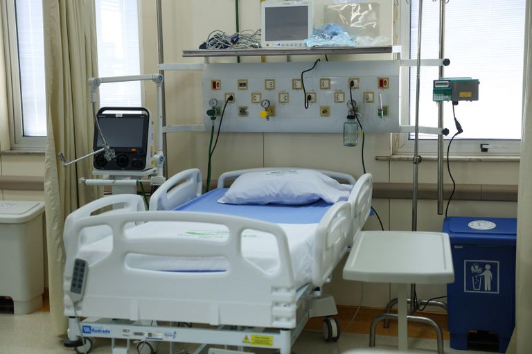 Foto de leito de hospital com aparelhos de monitoramento ao lado do leito.