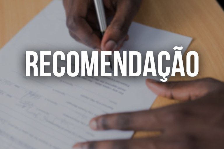 Foto de um par de mãos segurando uma caneta sobre um documento. A palavra "Recomendação" está sobreposta em letras brancas e grandes no centro da imagem.