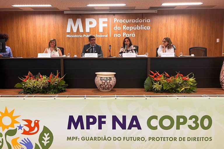 Quatro pessoas, duas mulheres e dois homens, sentadas atrás de uma mesa em um evento do MPF (Ministério Público Federal), Procuradoria da República no Pará, com um banner à frente dizendo "MPF NA COP30" e "MPF: Guardião do Futuro, Protetor de Direitos"