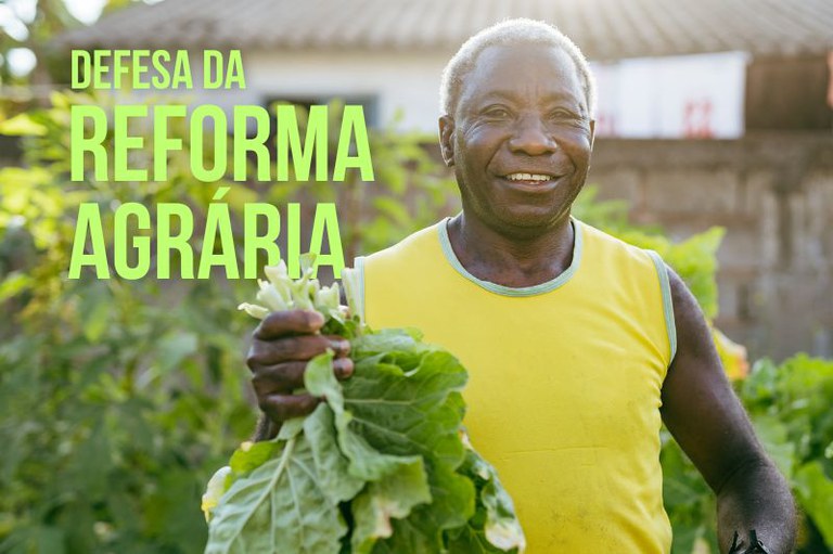 Foto de um homem sorridente, de camisa amarela, segura hortaliças verdes. À esquerda, em verde-limão, o texto: "Defesa da Reforma Agrária"
