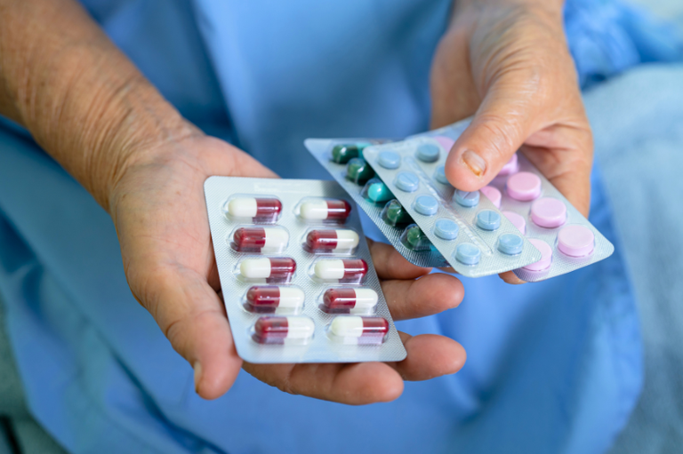 Foto mostra uma pessoa segurando algumas cartelas de medicamentos