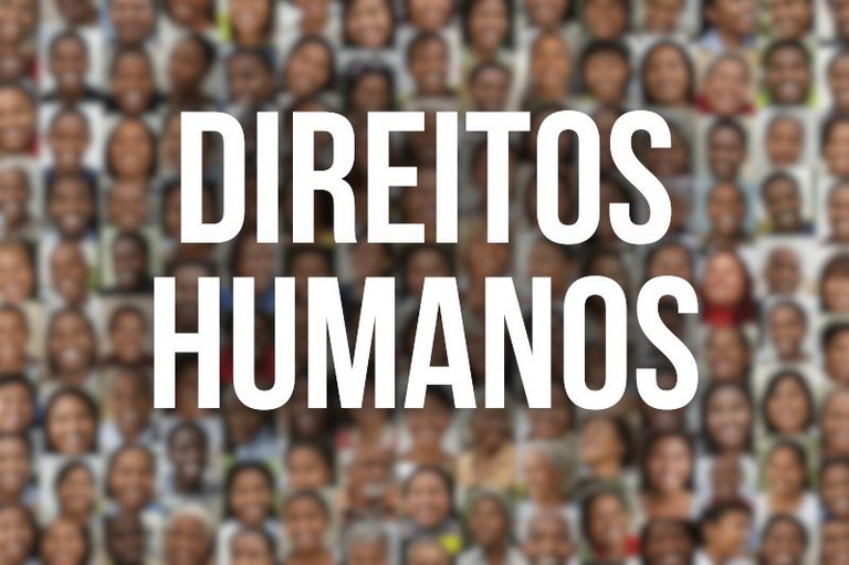 Foto desfocada com dezenas de rostos diversos ao fundo e o texto centralizado Direitos humanos escrito em letras brancas.