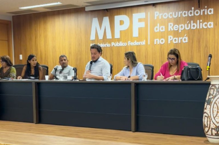 Foto da reunião, com uma mesa com seis pessoas sentadas, com um painel de madeira ao fundo onde se lê "MPF - Ministério Público Federal - Procuradoria da República no Pará.