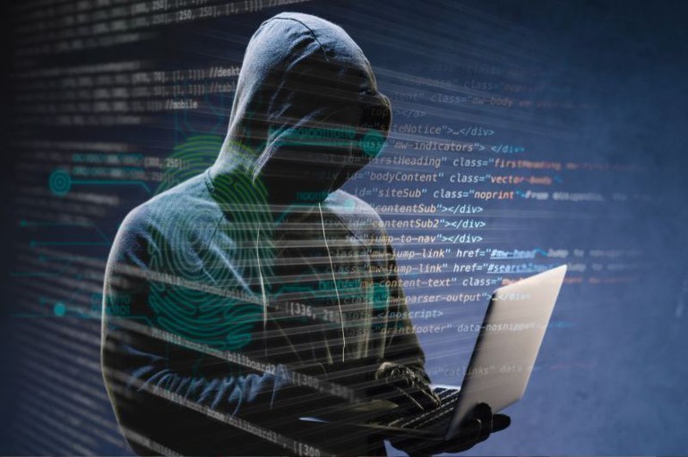 Figura de um hacker de capuz escuro e luvas, com o rosto na sombra, digitando em um laptop, sobreposto por códigos e dados digitais, incluindo uma impressão digital.