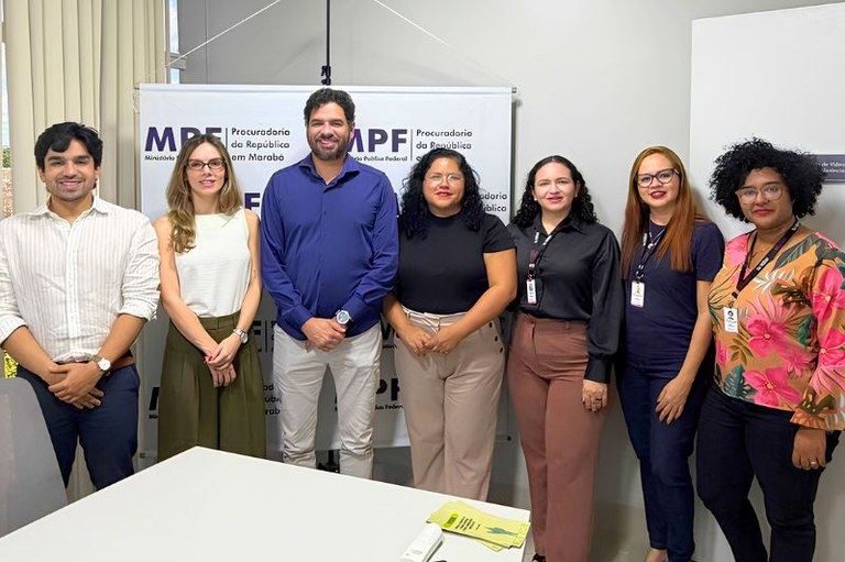 Sete pessoas posam lado a lado em frente a um banner branco com a inscrição MPF - Procuradoria da República em Marabá.
