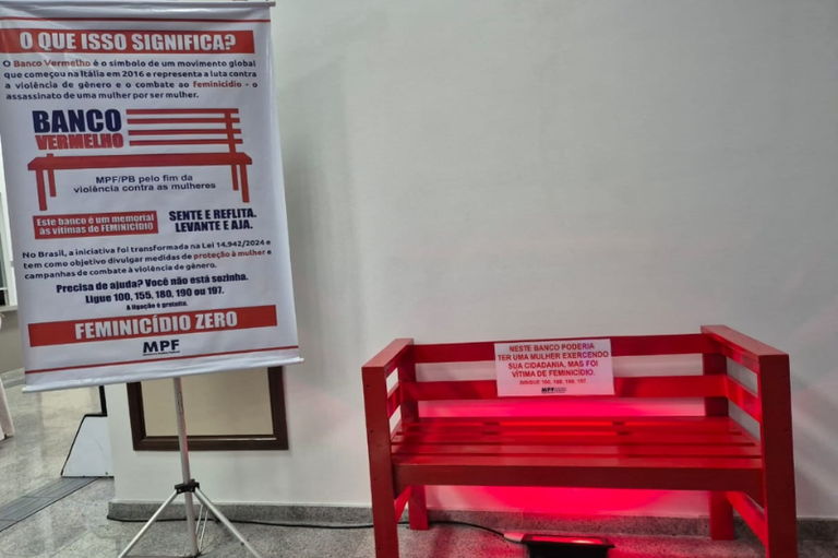 Foto mostra um banco vermelho instalado na sede do MPF e um banner de lona ao lado com informações sobre a campanha