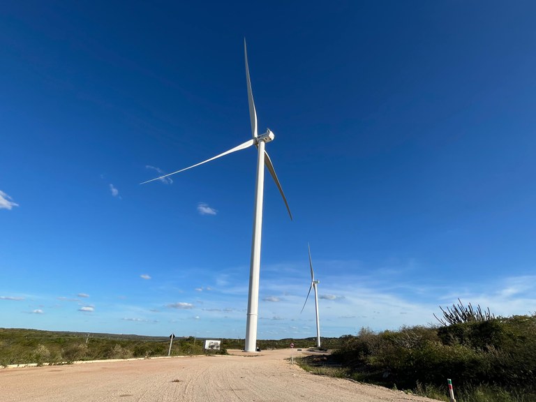 A imagem mostra torres de energia eólica numa paisagem da Caatinga