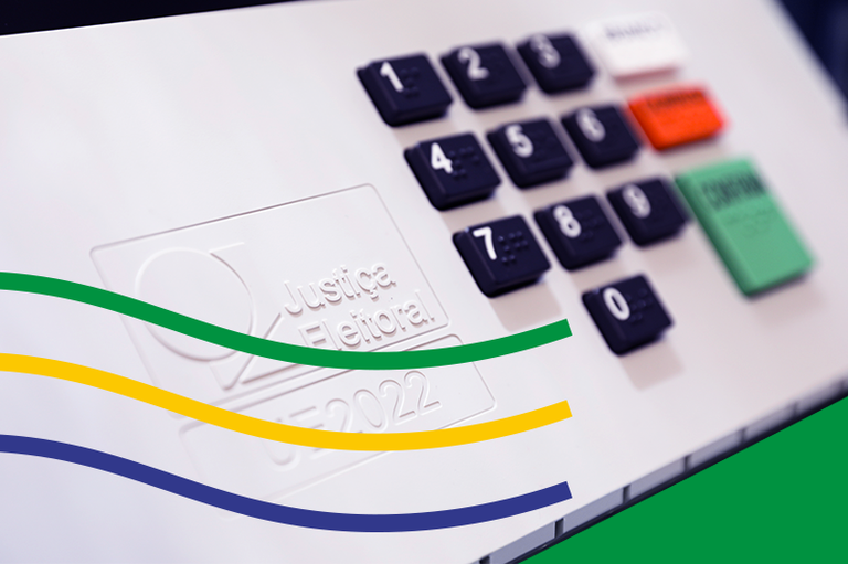 Foto mostra em detalhe as teclas da urna eletrônica, no canto inferior esquerdo três listras formando uma onda sendo uma verde, outra amarela e outra azul marinho e o canto inferior direito em verde bandeira