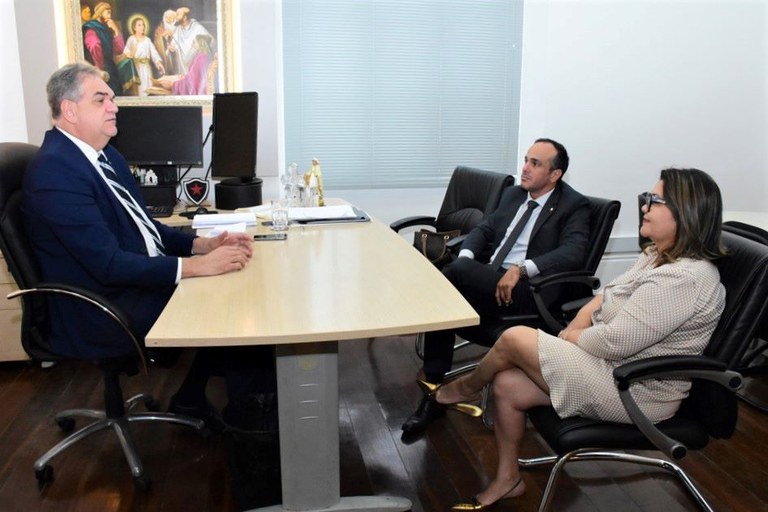 Fotografia da reunião entre o presidente do TJPB, desembargador Fred Coutinho, sentado à esquerda, com uma mesa de escritório a sua frente, e o procurador-chefe do Ministério Público Federal (MPF) na Paraíba, Bruno Galvão Paiva, e a procuradora regional dos Direitos do Cidadão, Janaina Andrade de Sousa, sentados à direita.