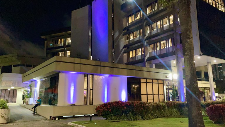 foto do edifício-sede iluminado na cor roxa.