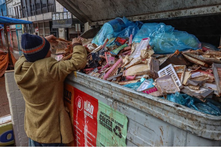 Foto de um morador de rua procurando no lixo algo que seja útil para ele