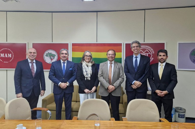 Foto mostra os participantes da reunião em uma sala com bandeiras de movimentos sociais e minorias
