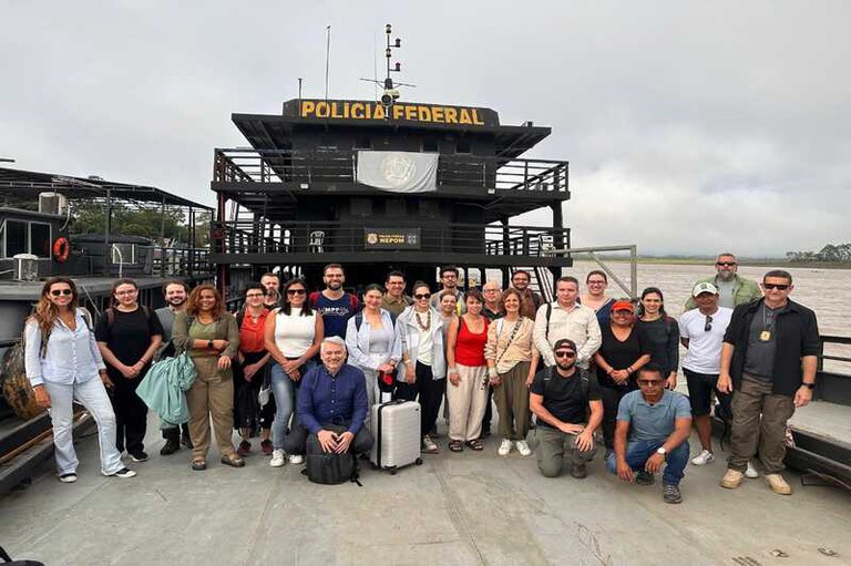 Imagem mostra 27 pessoas em pé em embarcação da Polícia Federal