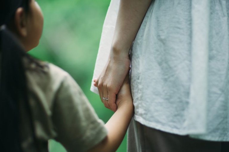 Imagem em detalhe de uma criança segurando a mão de um adulto