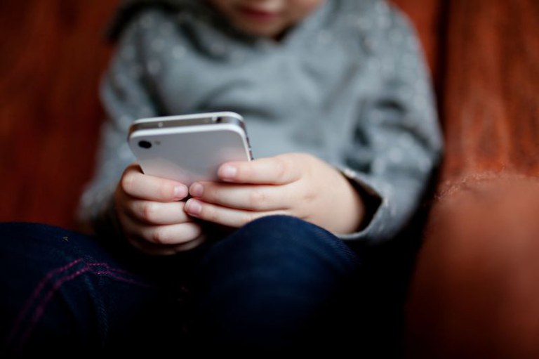 Imagem em detalhe de uma criança mexendo no celular