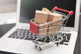 Imagem de um carrinho de compras com alguns itens, sobre um notebook aberto.