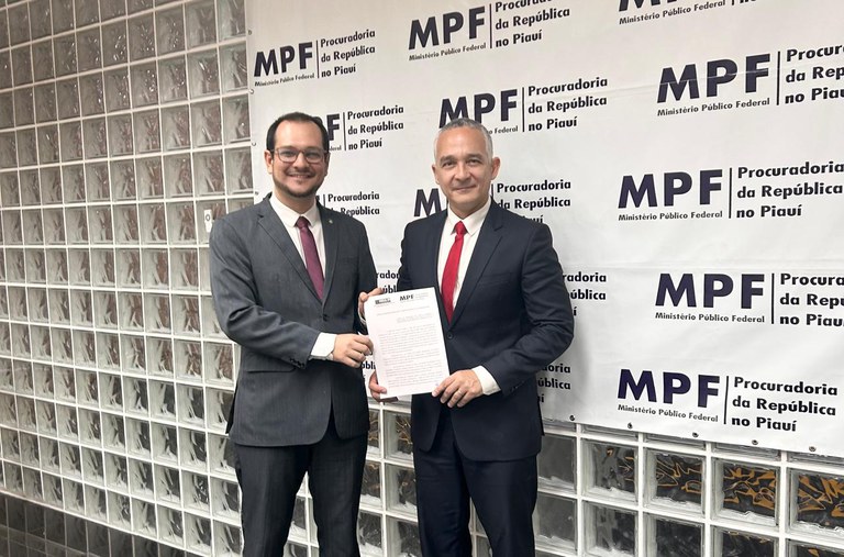 Registro fotográfico do procurador-chefe da Procuradoria da República no Piauí, Marco Aurélio Adão, e do presidente do Crea/PI, Hércules Lima de Medeiros, na sede do MPF em Teresina (PI)no dia 27 de fevereiro de 2025. Os dois estão de pé segurando o documento que firma a parceria técnica entre os dois órgãos. Atrás das duas autoridades há um banner do MPF.