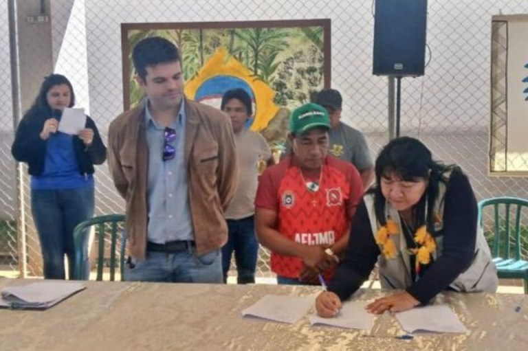 Imagem mostra indígenas assinando o acordo