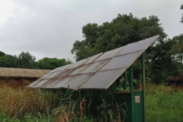 Foto colorida mostra área da ilha da Cotinga onde está instalado um painel de energia solar, rodeado por vegetação e com marcas de sujeira