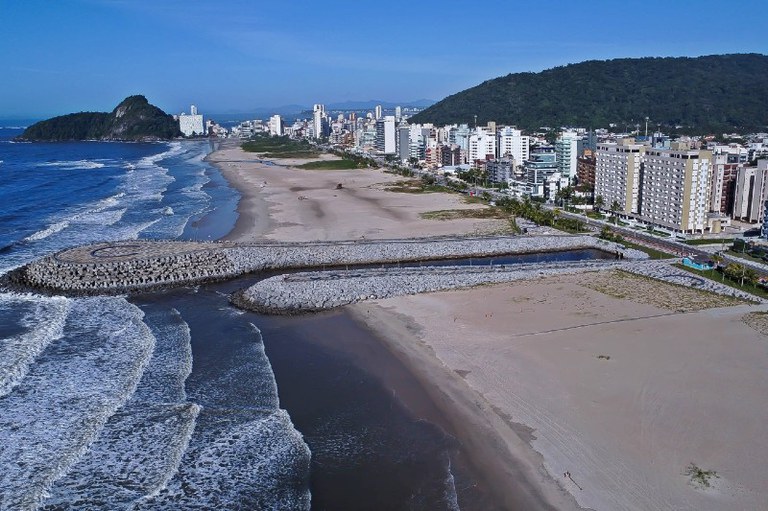 Foto mostra um píer de pedra que avança sobre a o mar em Matinhos