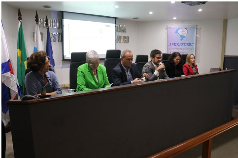 Imagem mostra mesa do evento com palestrantes