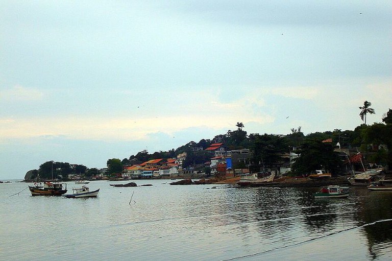 Foto do mar da Pedra de Guaratiba mostra barcos na água, casas ao redor e vegetação